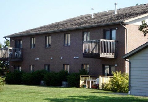 A brick building with a balcony and a small garden in front.