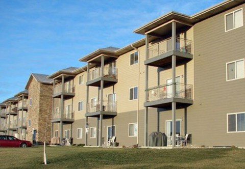 Apartment complex with a red car parked in front.