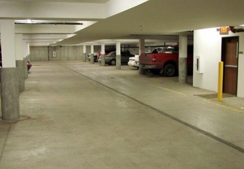 A parking garage with a red car parked in the middle.