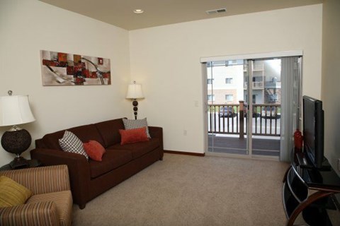 A living room with a brown couch and a painting on the wall.