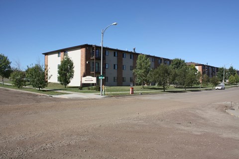 Apartment complex with a parking lot in front.