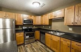 A kitchen with wooden cabinets and a stainless steel refrigerator.