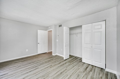 the living room of an apartment with white walls and wood floors
