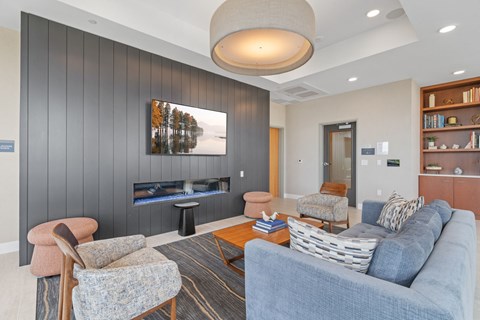 A living room with a grey couch, a chair, a coffee table, and a painting on the wall.
