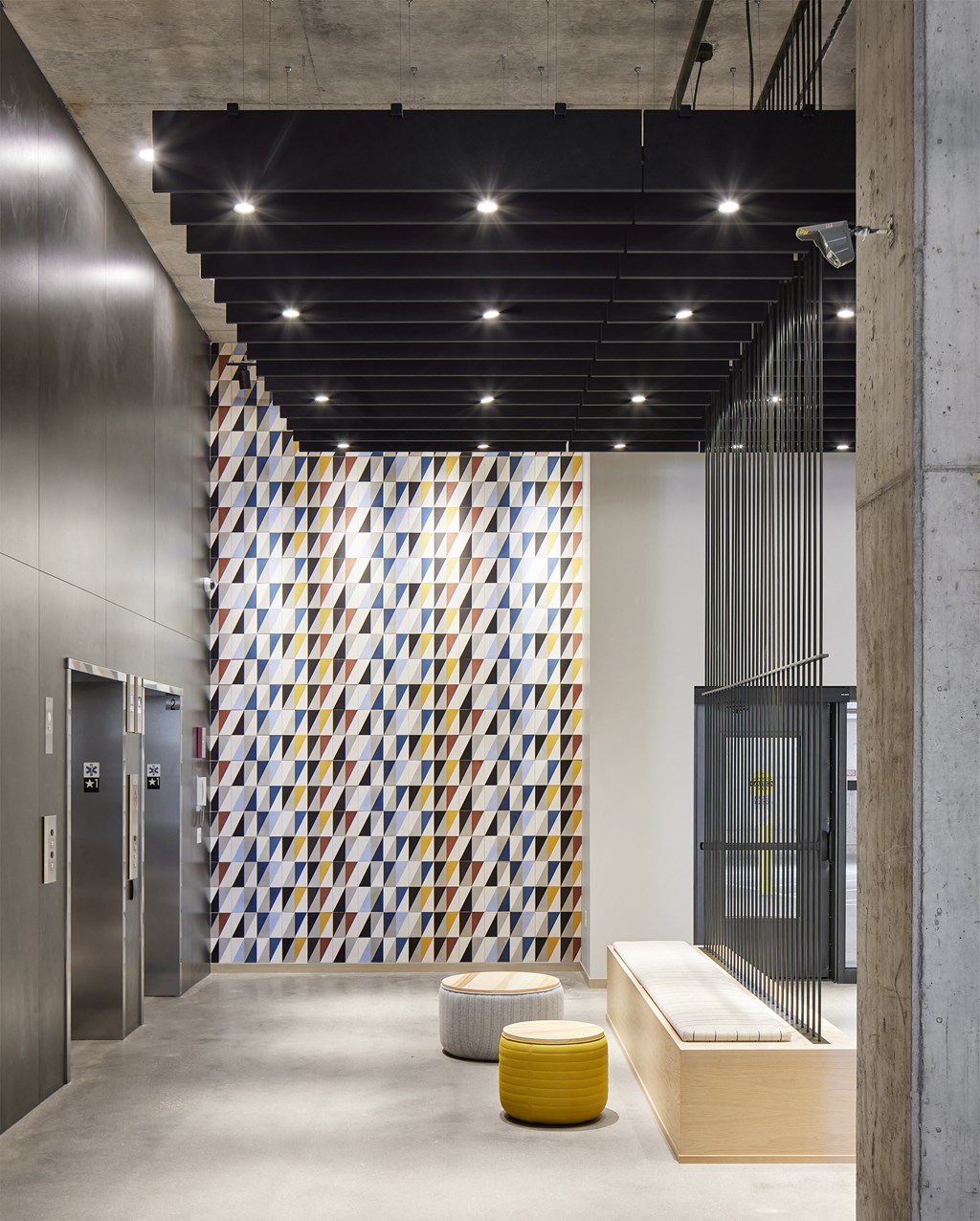 a geometric patterned wall in the lobby of a building with elevators