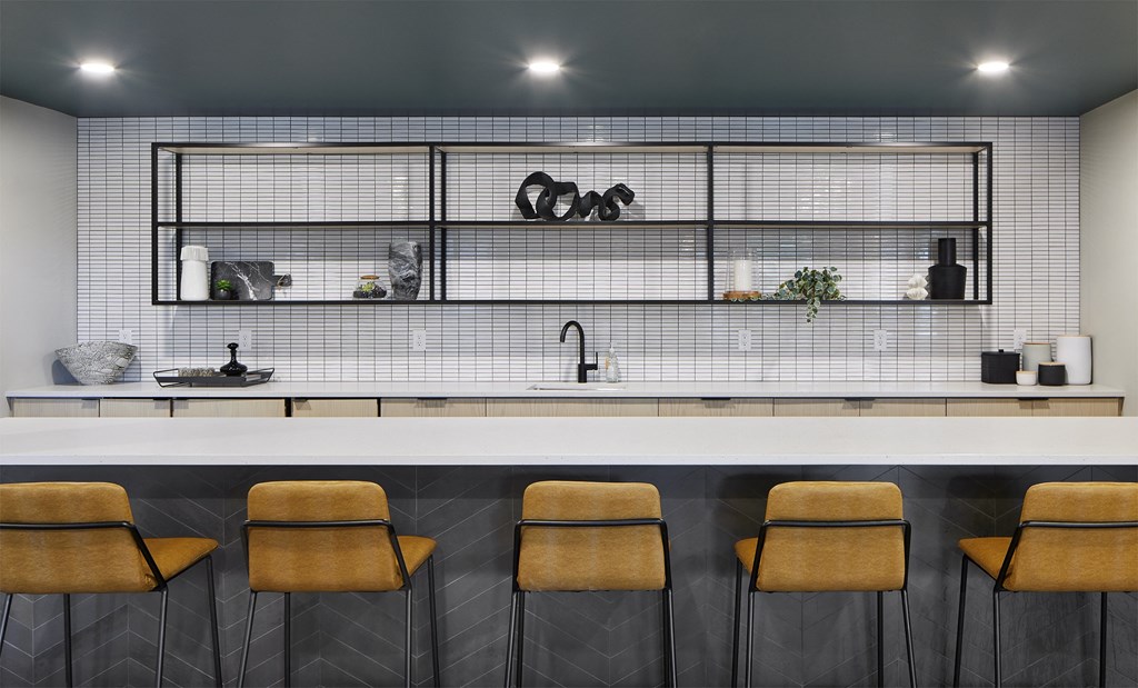 a bar with four stools in front of a white counter and a glass wall