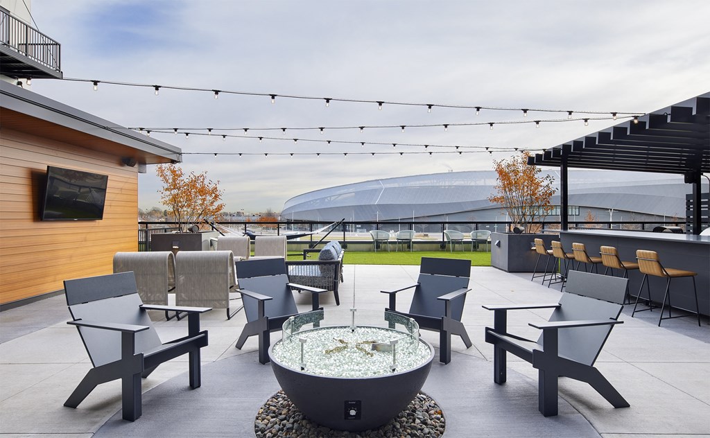 a rooftop patio with tables and chairs and a fire pit