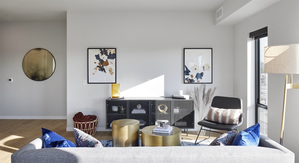 a living room with a couch and a chair and a desk and a window