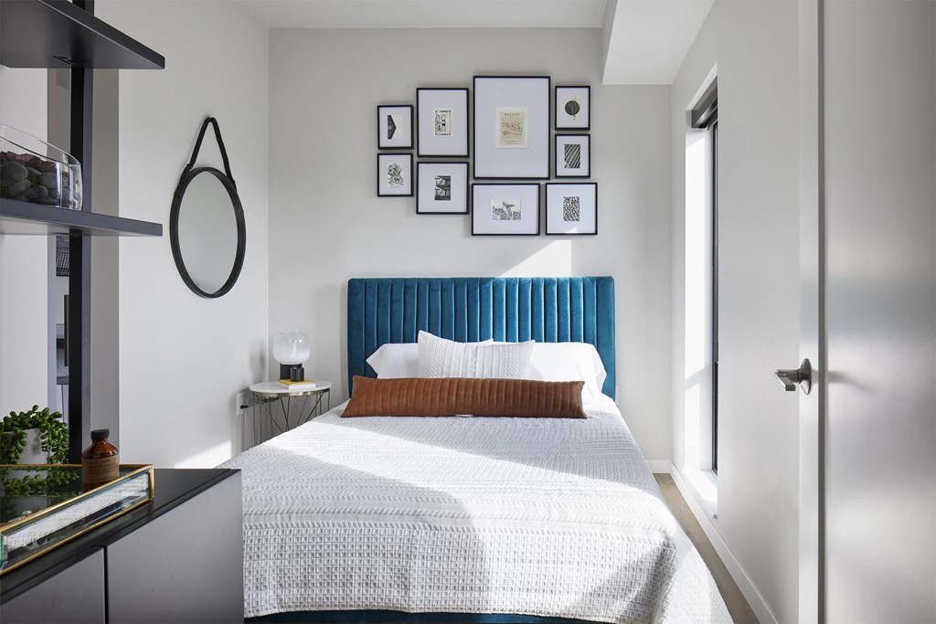 a bedroom with a bed and a blue headboard and pictures on the wall