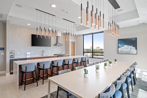 A modern kitchen with a long table and bar stools.