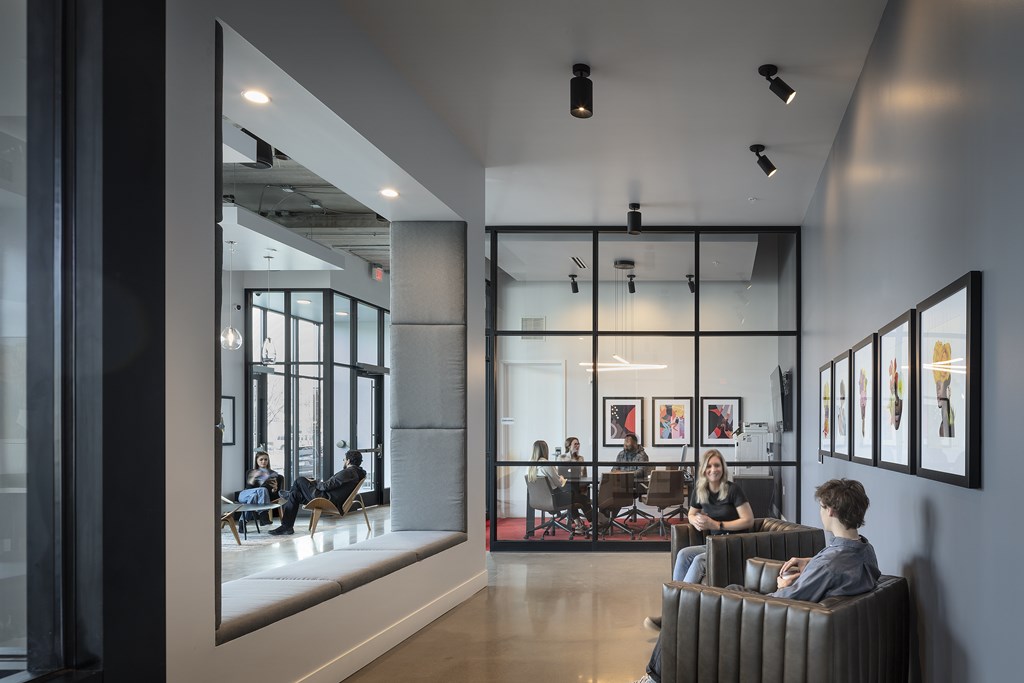 a group of people sitting in chairs in a room with large windows