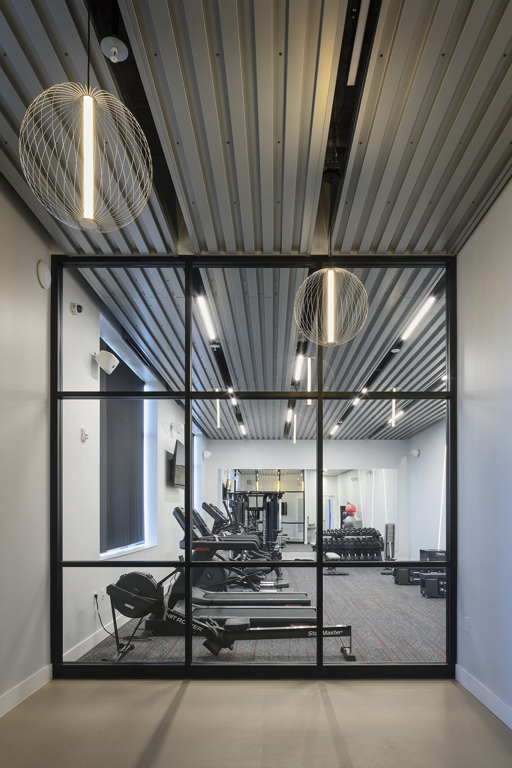 a view of a gym with weights machines and a large glass window