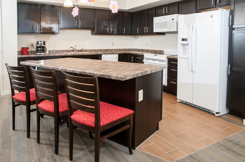 a kitchen with a granite island and black cabinets and white appliances