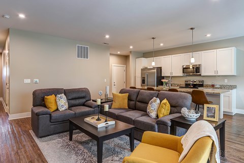 A modern living room with grey couches and yellow pillows.