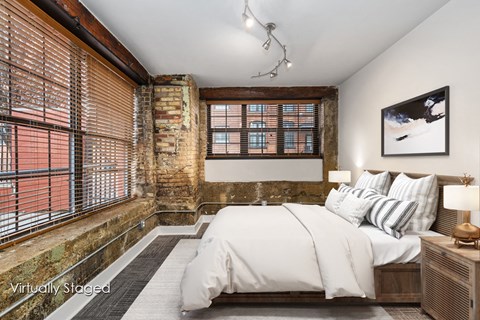 A bedroom with a large bed and a window with blinds.