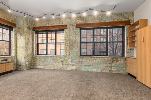 A room with a brick wall and string lights on the ceiling.