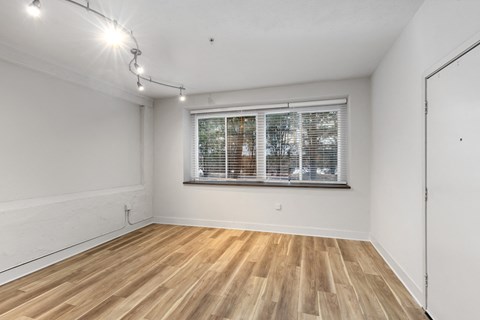 A room with wooden flooring and a window with blinds.