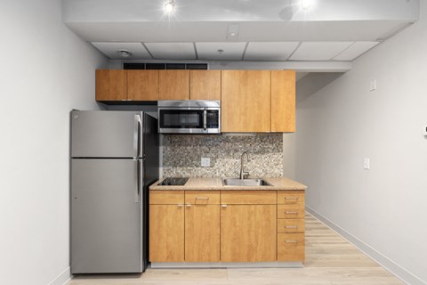 A kitchen with a refrigerator, microwave, and sink.