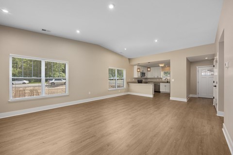 A spacious room with wooden flooring and a large window.