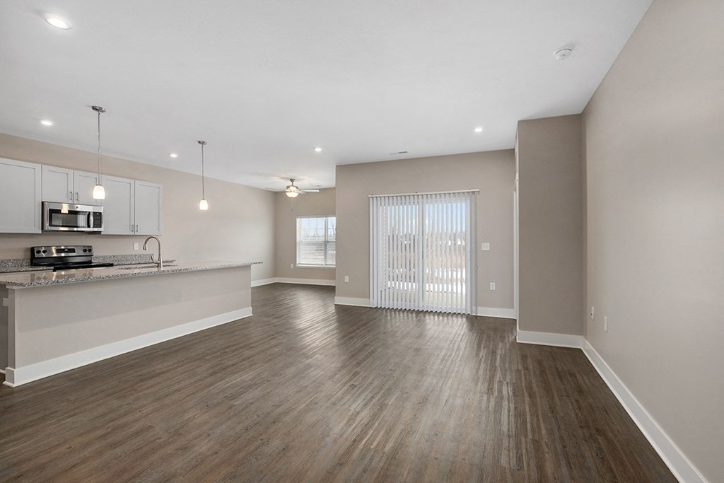 an empty living room and kitchen with wood flooring and a window