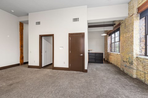 A room with a carpeted floor and a brick wall.