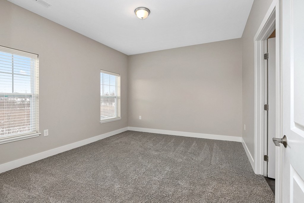 an empty living room with two windows and a door