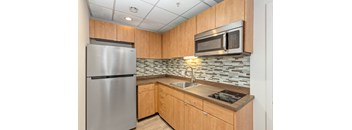 A kitchen with a stainless steel refrigerator and a microwave above the stove.