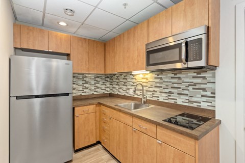 A kitchen with a stainless steel refrigerator and a microwave above the stove.