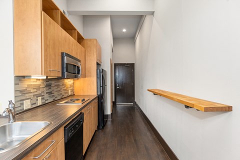 A kitchen with wooden cabinets and a black refrigerator.