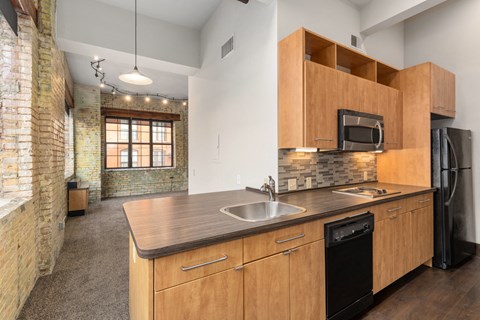 A kitchen with wooden cabinets and a brick wall.