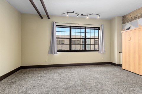 A room with a large window and a grey carpet.