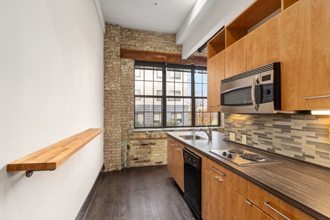 A kitchen with wooden cabinets and a brick wall.