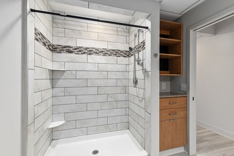 A bathroom with a white tiled shower and a wooden cabinet.