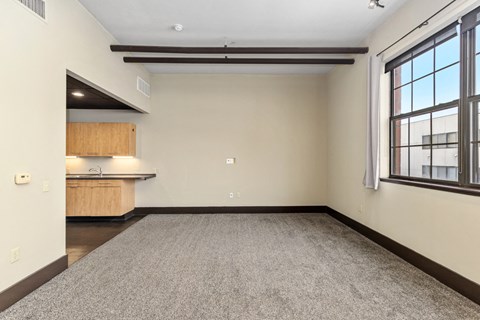 A room with a carpeted floor and a window on the right side.