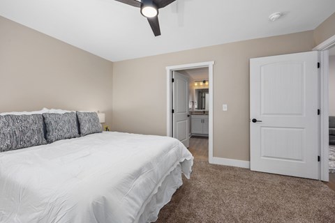 A bedroom with a white bed and a ceiling fan.
