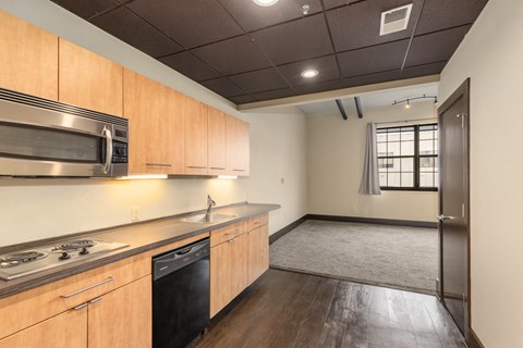 A kitchen with wooden cabinets and a black dishwasher.