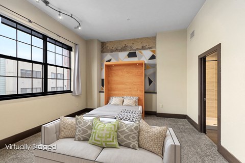 A bedroom with a large bed and a window with blinds.