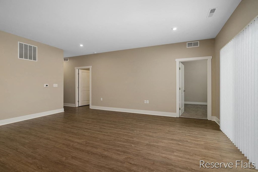 an empty living room with a wood floor and white walls
