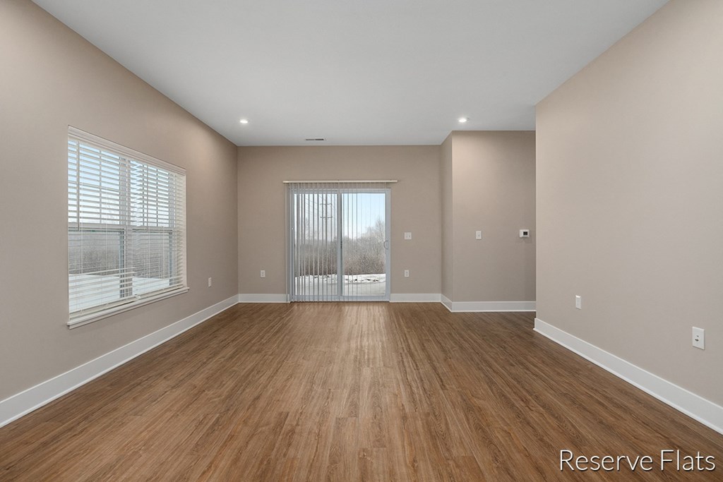 an empty living room with wood flooring and a sliding glass door