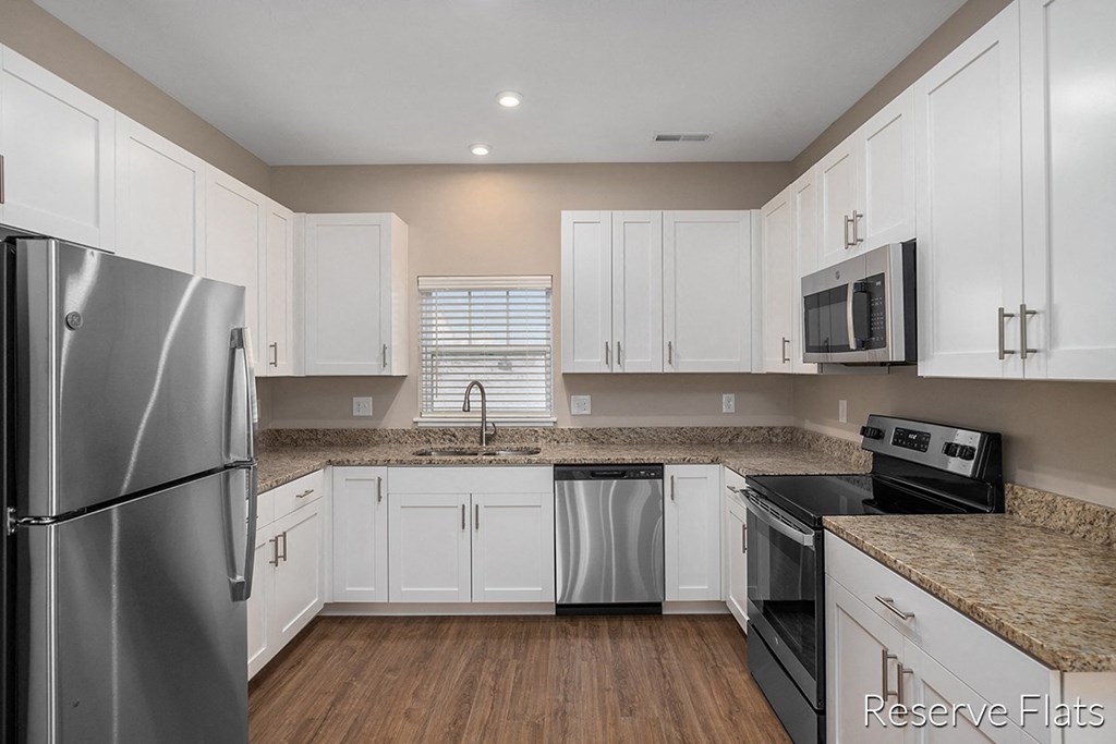 a white kitchen with stainless steel appliances and white cabinets