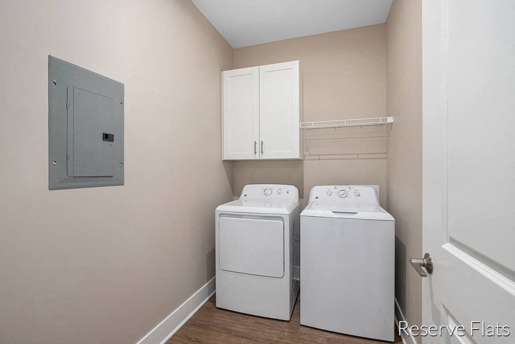 a laundry room with a washer and dryer and white cabinets