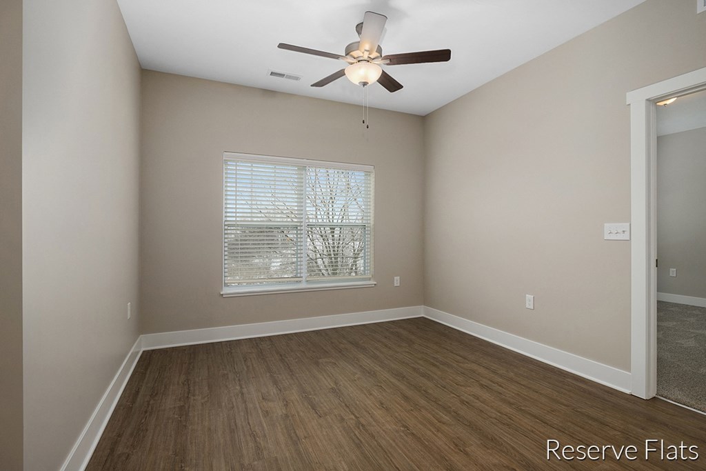 an empty room with a ceiling fan and a window
