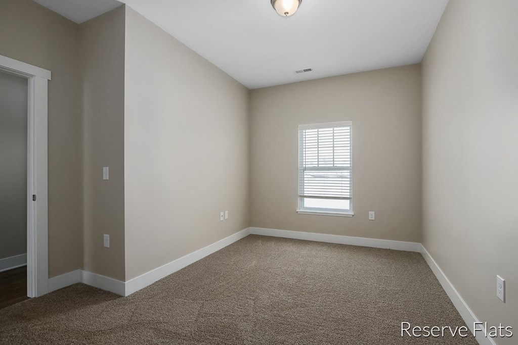 a empty room with carpet and a window