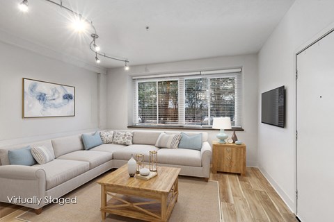 A living room with a couch, coffee table, and a painting on the wall.