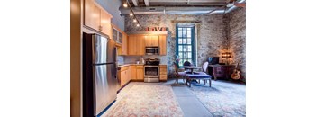 A kitchen with a refrigerator, oven, and a dining table with chairs.