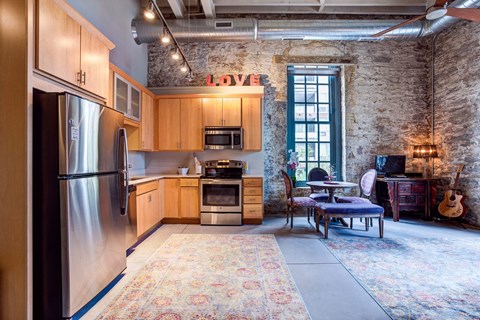 A kitchen with a refrigerator, oven, and a dining table with chairs.
