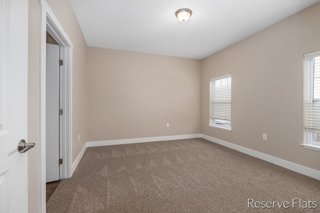 a empty living room with carpet and a door to a closet