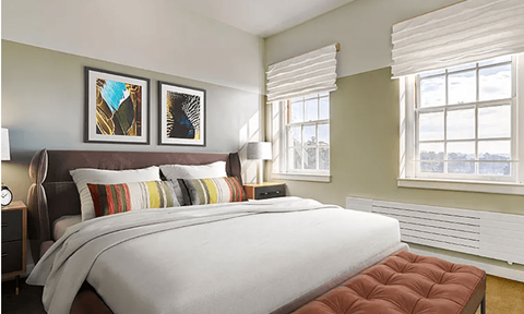 A bedroom with a large bed and two pictures on the wall.