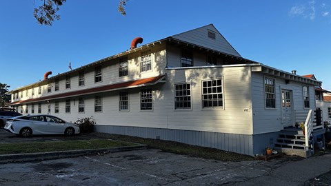 A white building with a red roof and a car parked in front.