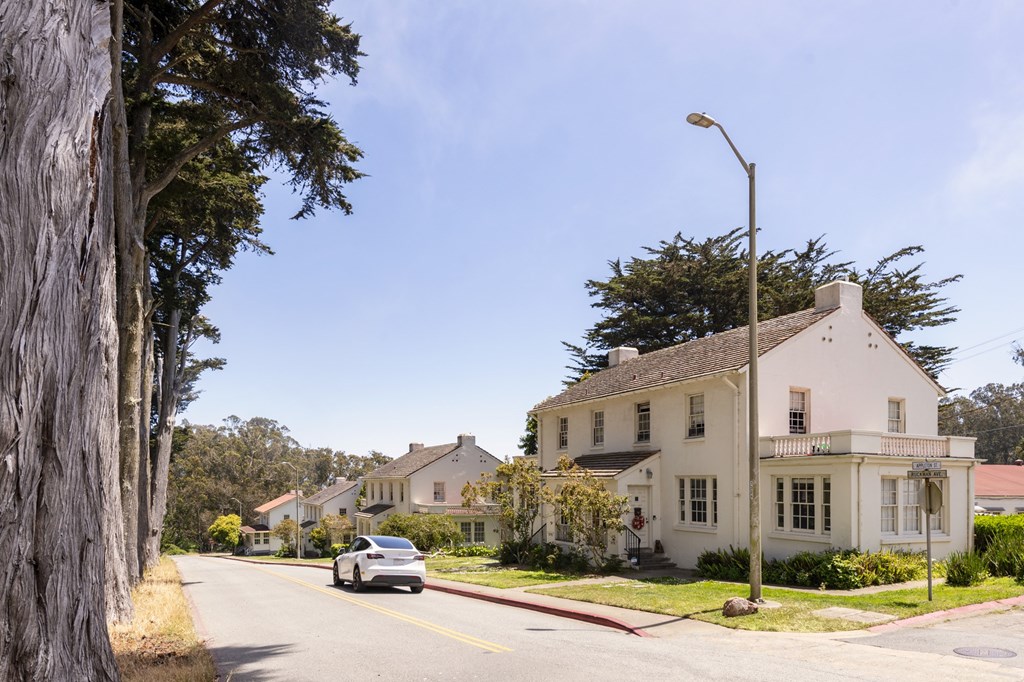 A white house with a grey car parked in front of it.